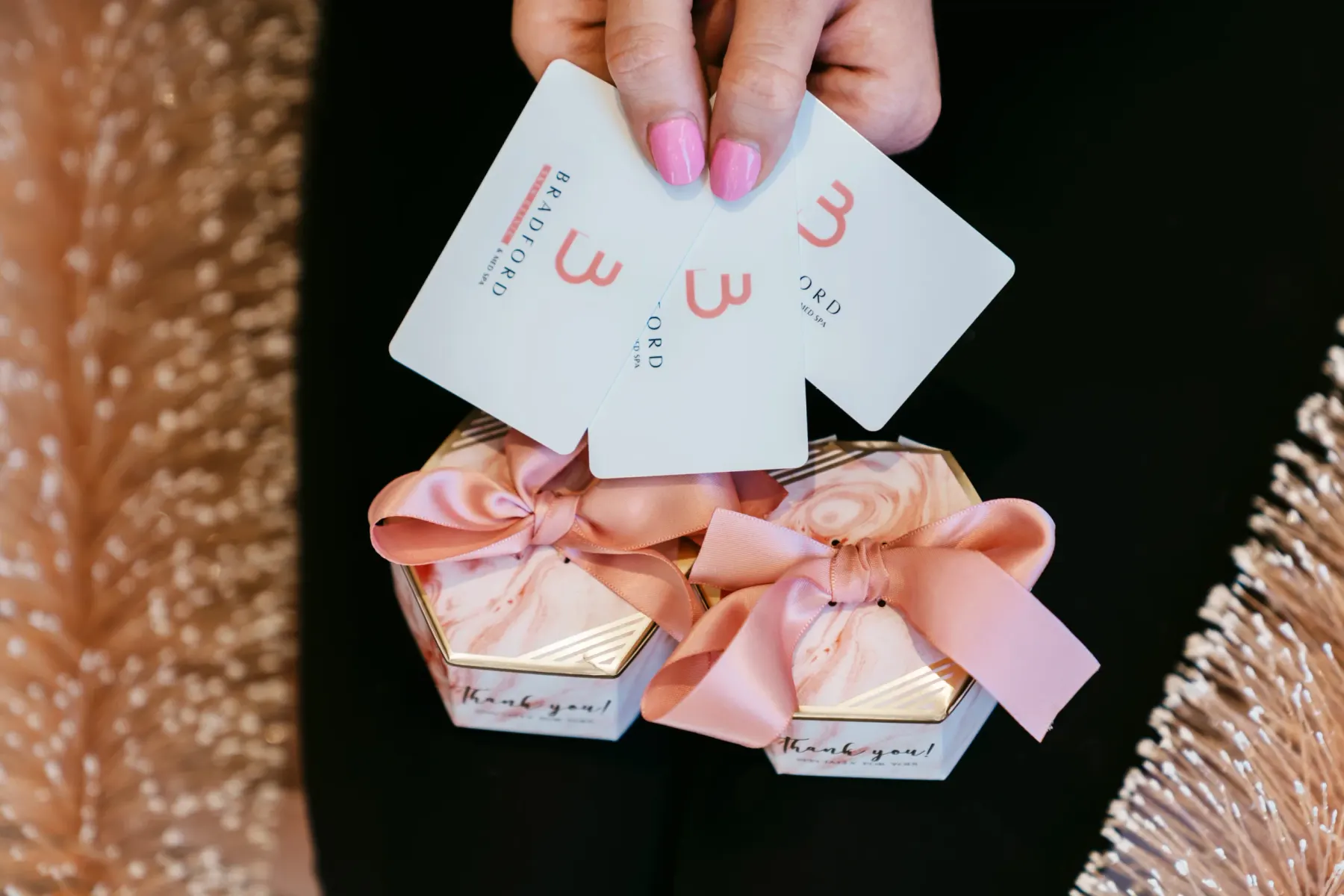 Bradford Skin Clinic gift cards held above two ribboned gift boxes