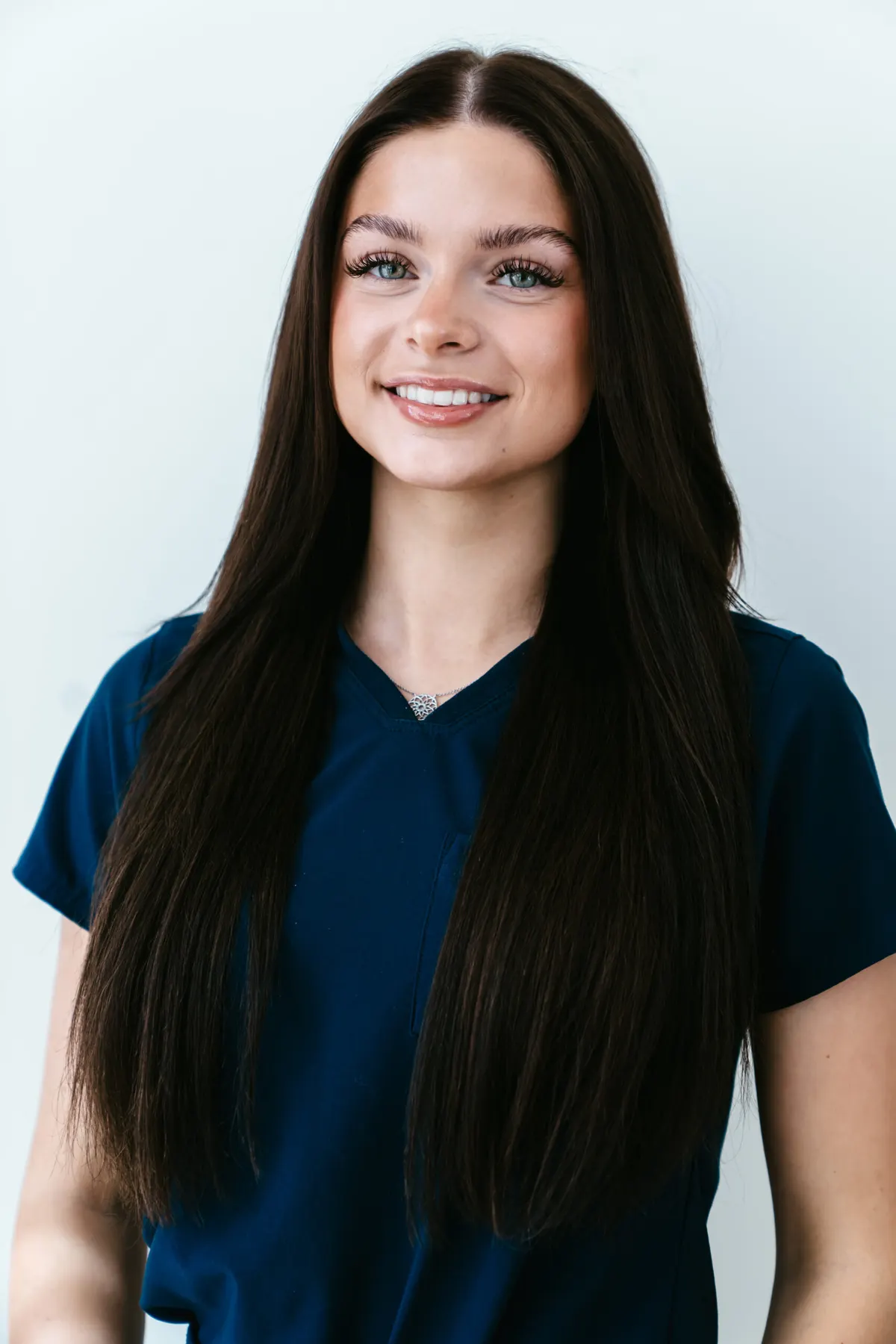 A member of the clinic team photographed against a pale wall in Bradford Skin Clinic navy scrubs.