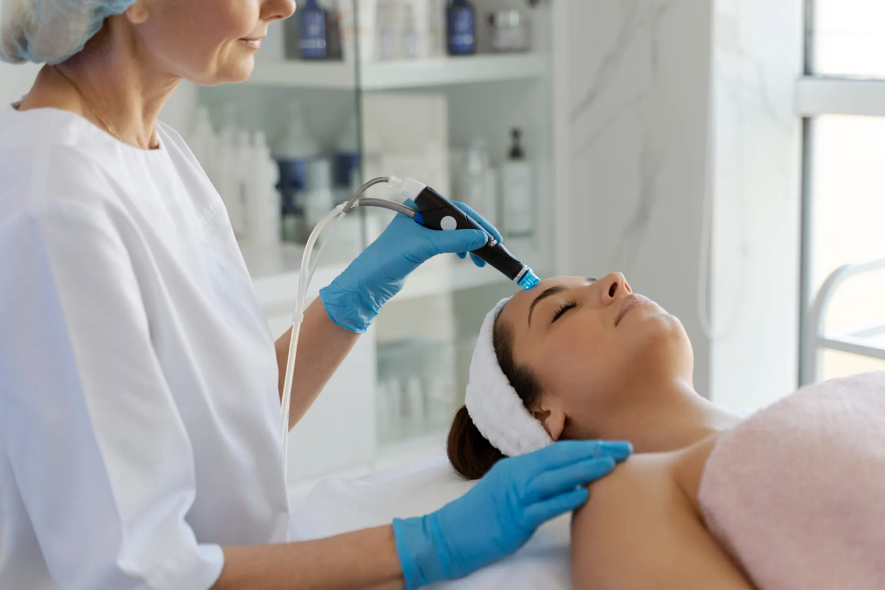 HydraFacial device passing over a client's forehead in the treatment room
