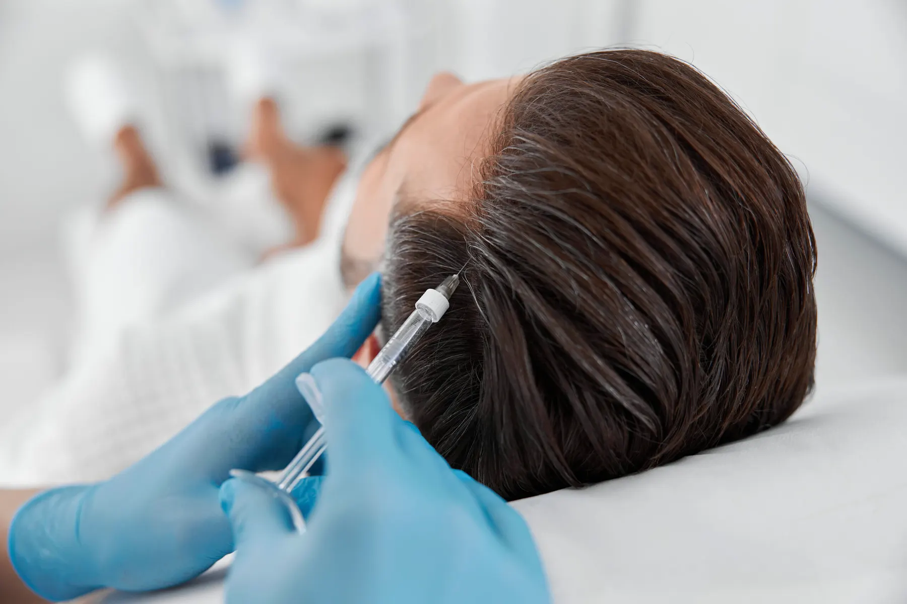 A client receiving a scalp treatment in a bright modern clinic room