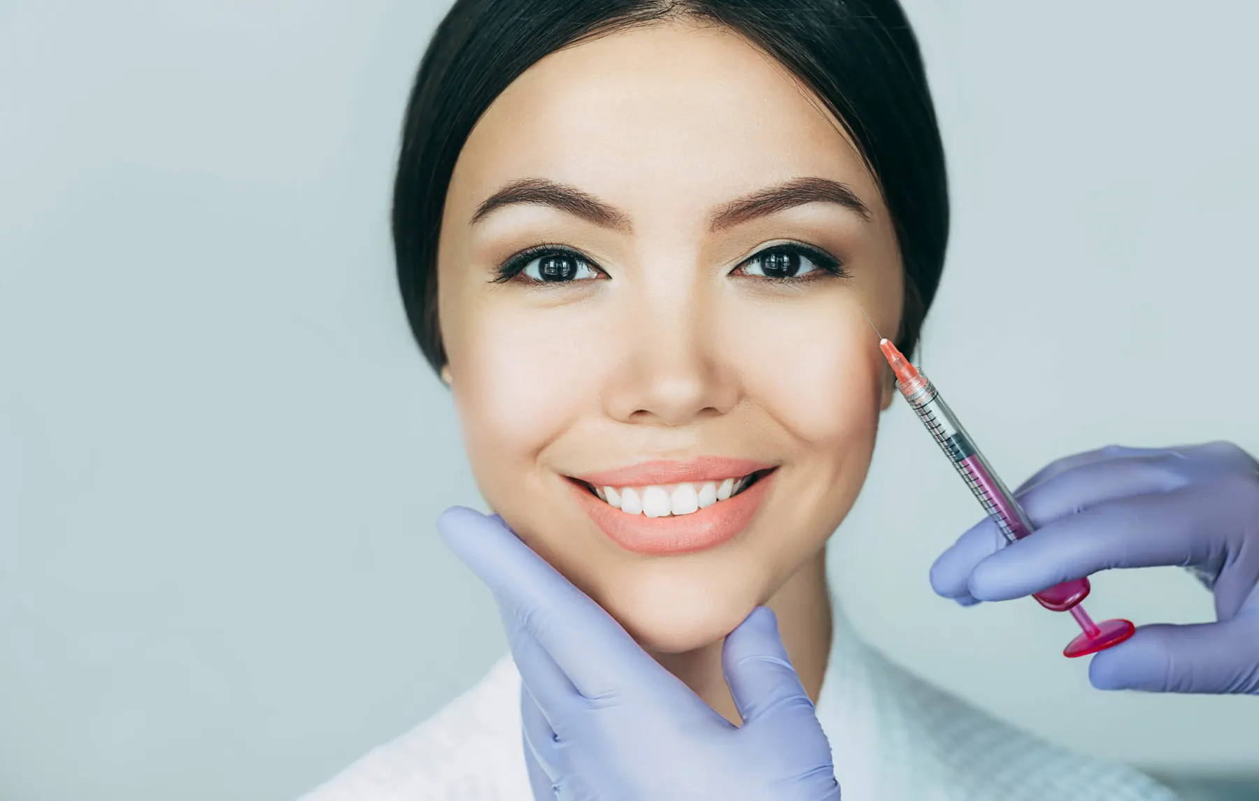 A close-up of a fine needle delivering a skinbooster into the cheek