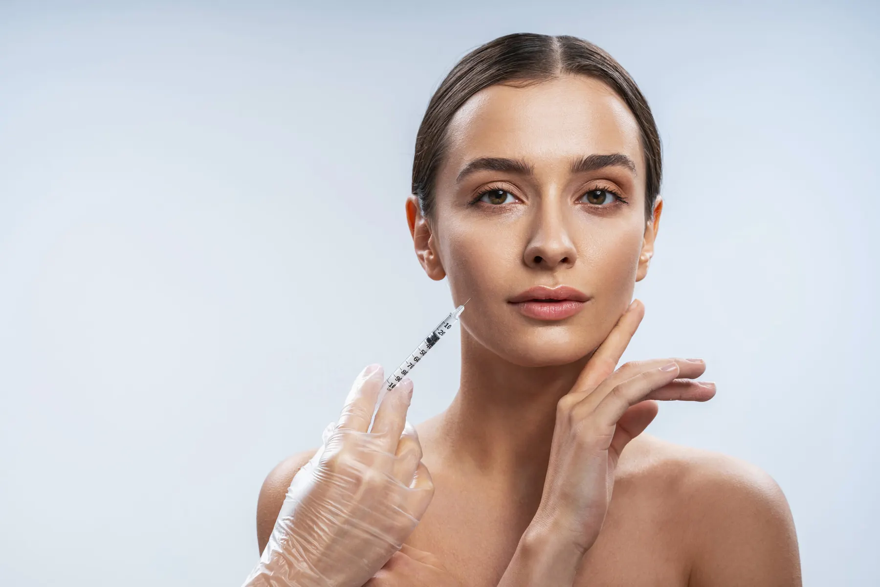 An injector treating a client's midface in a clinical setting
