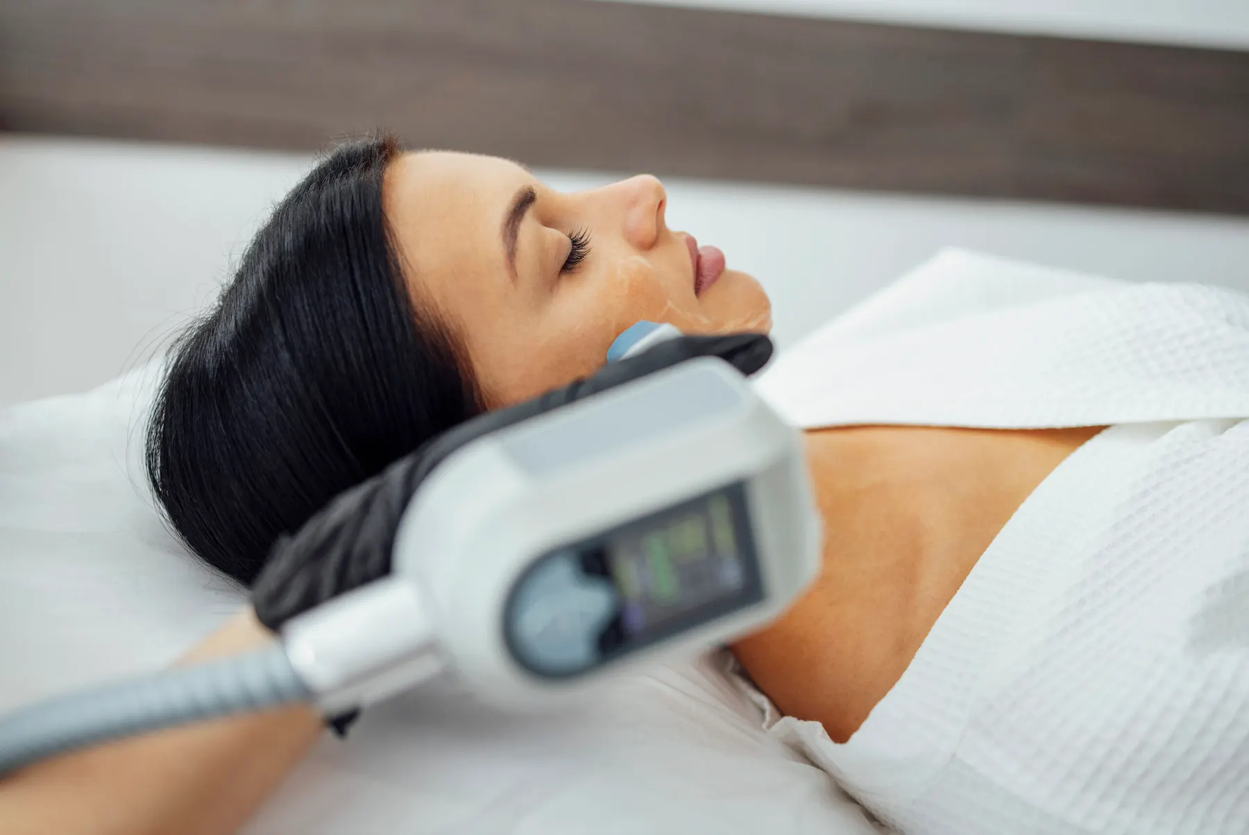 A clinician performing laser resurfacing on a client's face at the clinic