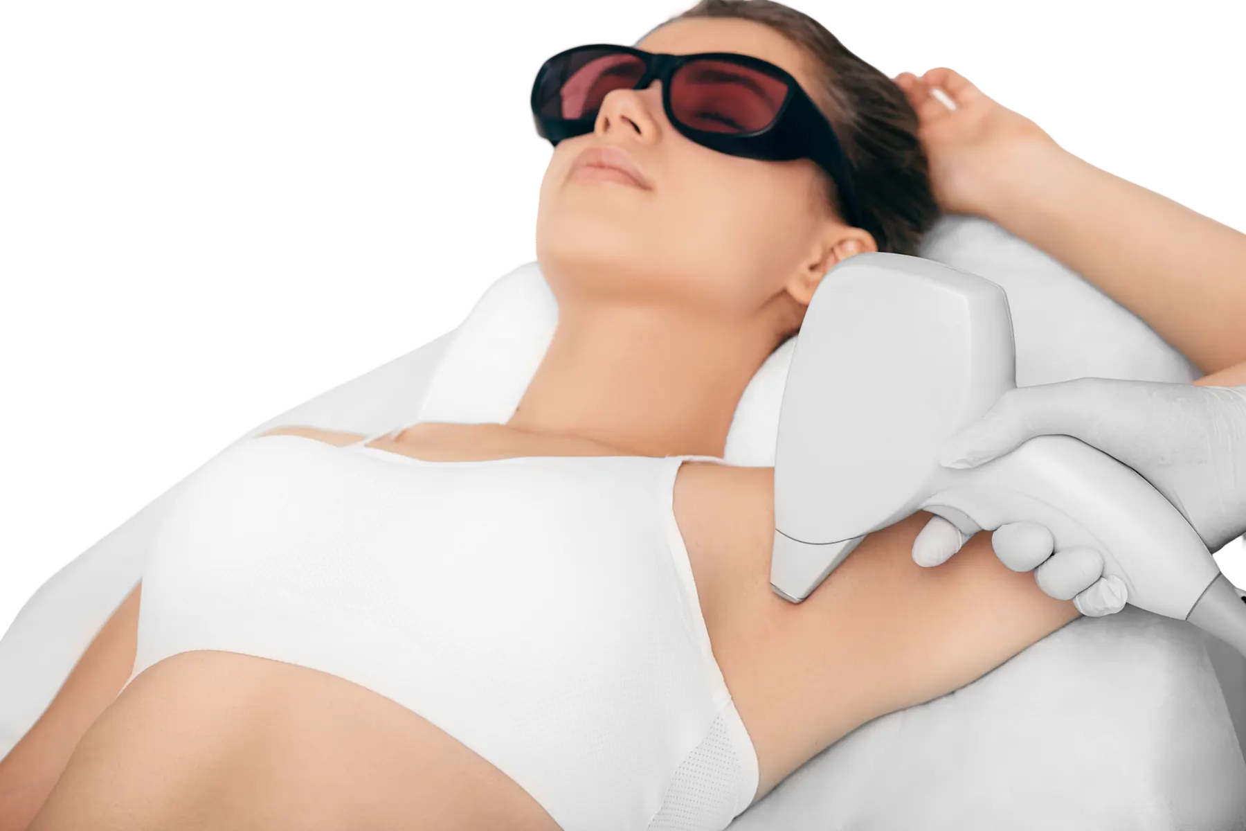 A woman in white underwear and dark protective goggles lies back with one arm raised while a gloved technician treats her underarm with a laser handpiece.