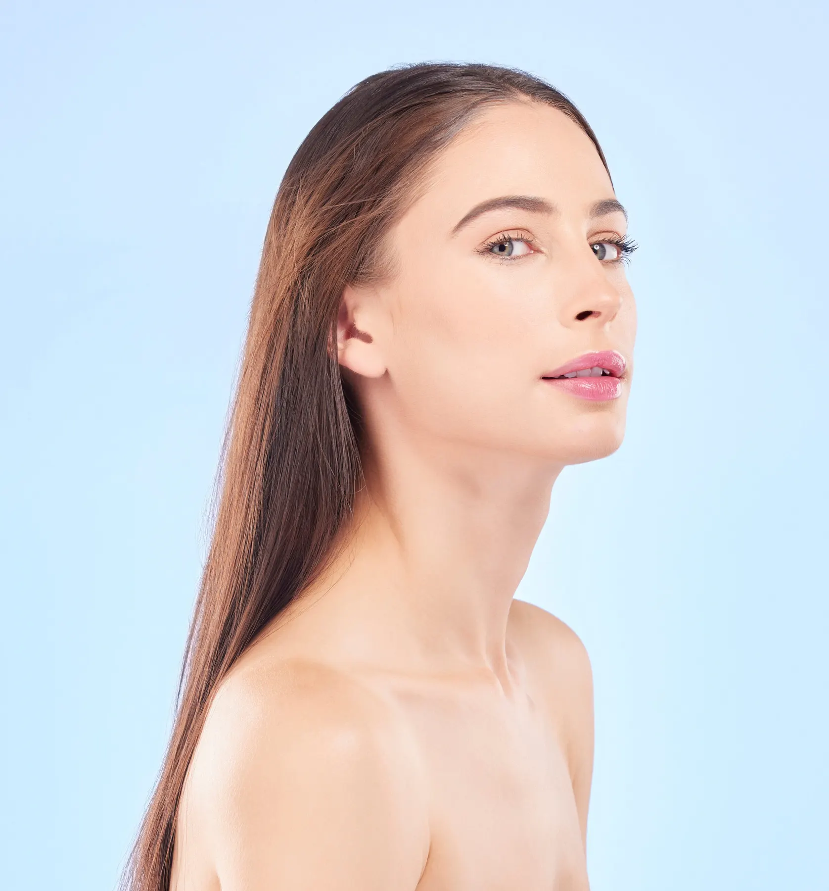 A brunette woman in three-quarter profile against a pale blue studio ground