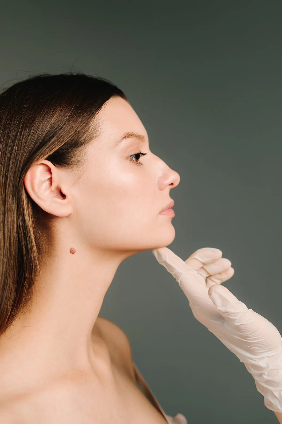 Profile of a client having her jawline assessed by a gloved practitioner