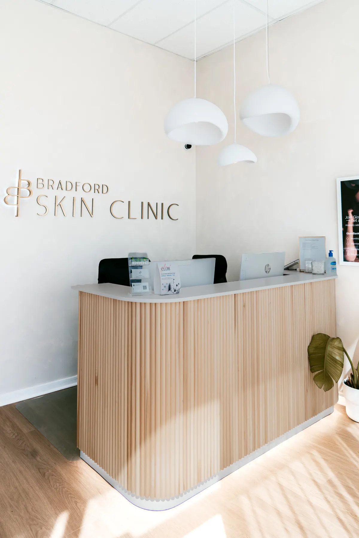 The Bradford Skin Clinic reception desk, with the clinic name in brushed gold on the wall behind it.